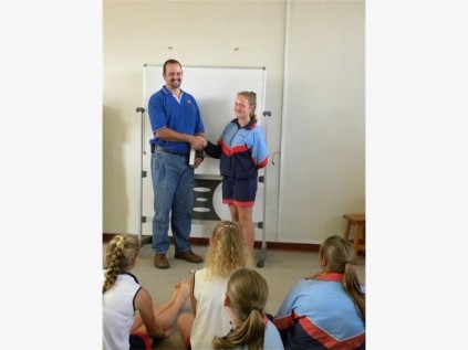 Alfonso Middleton van die Ekonomiese Bestuurs Wetenskappe 'beklink 'n transaksie' met  gr 7 leerling Jessé Nel.