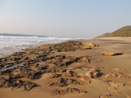 An outcrop of golden rocks breaks the endless vista of golden sand.
