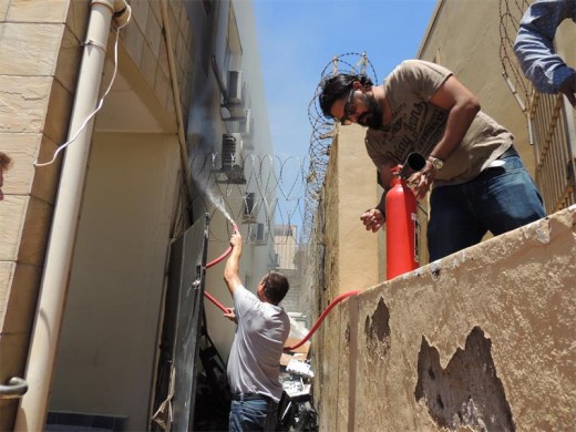 South Coast Herald staff member Brennan Raymond  (right)  primes the Herald's fire extinguisher  while former fire fighter Theunis Greyling turns a fire hose on the flames.