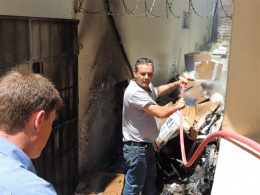 Raefe Dyer (left), who works in the Nashua building, offers his assistance as Theunis Greyling douses the flames.