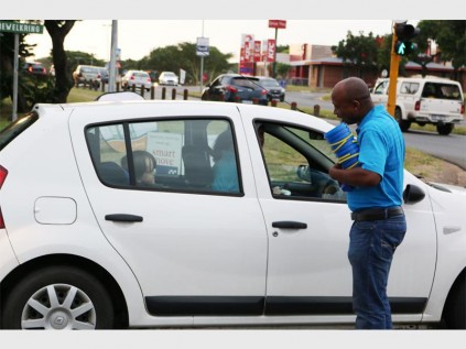 Sibusiso Makhanya hand out a gift and a pamplet of water saving tips to a motorist
