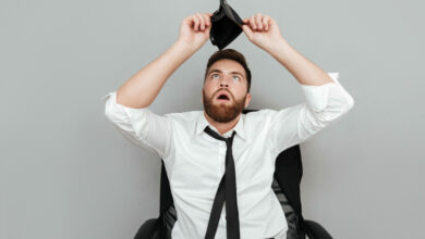 Frustrated surprised bearded man in white shirt showing empty wallet