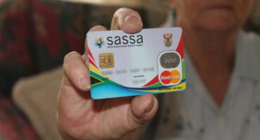 Person's hand holding a Sassa grant payment card