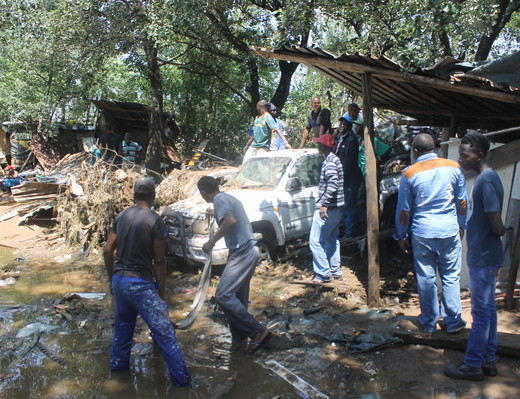 Setswetla Informal Settlement dwellers retrieve a car that was washed away by the flooded Jukskei River.