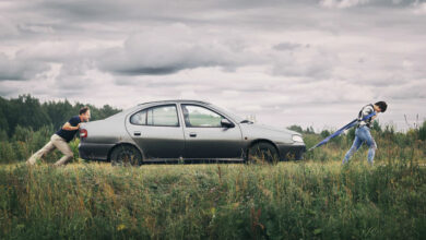 Couple pushing their broken car down the country road