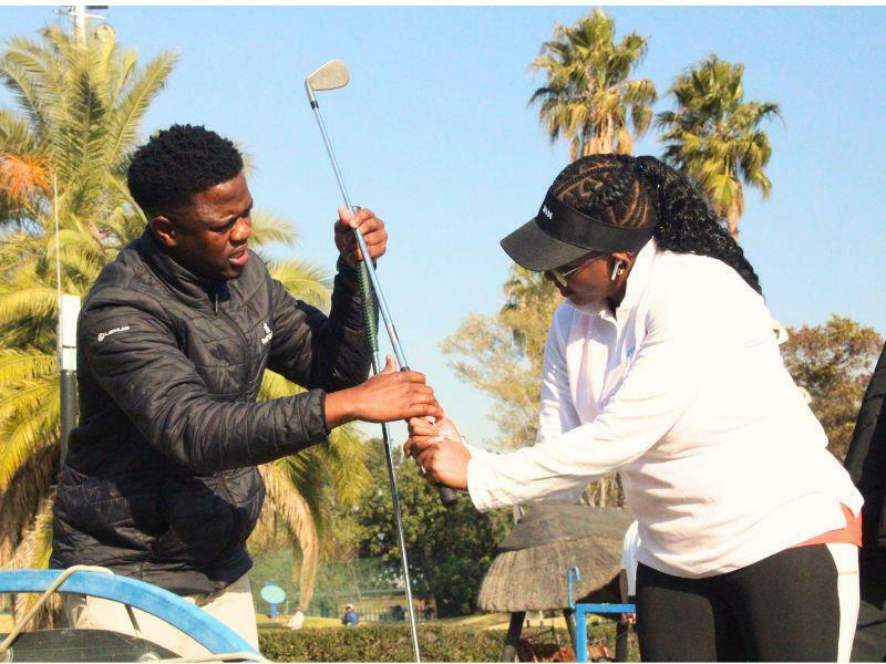 Golf coach Israel Moyo shows Moumisa Titus how to hold a golf club. Photo: Comfort Makhanya