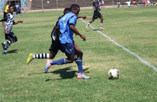 Thabiso Tshenye runs with the ball while an Alex Black Poison player chases him.