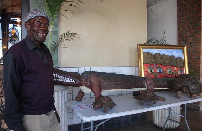 Artist Richard Ngojo stands next to his artworks titled the Predator, Impiloende, Village (Home sweet home) at the auction. Photo: Zanele Mfaba