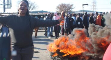 A Friendship Town Estate resident stands next to a burning tyre during a protest over prolonged electricity and water outages in Commercia Extension 9 on September 3. Photo: Comfort Makhanya