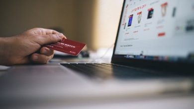 An image depicting a hand holding a bank card with busy with online shopping.