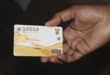 A picture of a hand holding a SASSA card in front of a dark back ground.