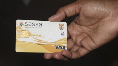 A picture of a hand holding a SASSA card in front of a dark back ground.
