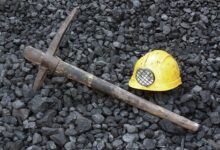 A yellow hat and a pick lying on coal at a coal mine.