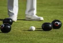 A generic image of bowls on strategically placed on the bowling greens with the legs and feet of a bowler seen in the background.