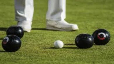 A generic image of bowls on strategically placed on the bowling greens with the legs and feet of a bowler seen in the background.