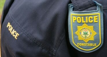 A police officer in uniform, showing the SAPS emblem