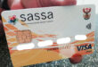 A hand holding South African Social Security Aid (SASSA) card.