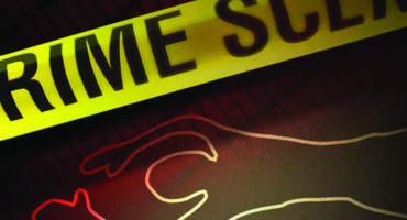 Photo of yellow take with words of crime scene stretched over the white chalk outline of a person lying on the ground.