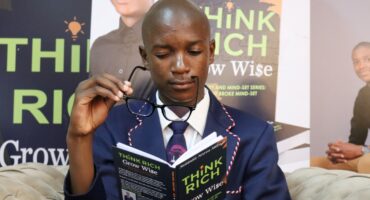 A 17-year-old student in a school uniform reads his debut book Think Rich Grow Wise during its launch at Newcastle Library.