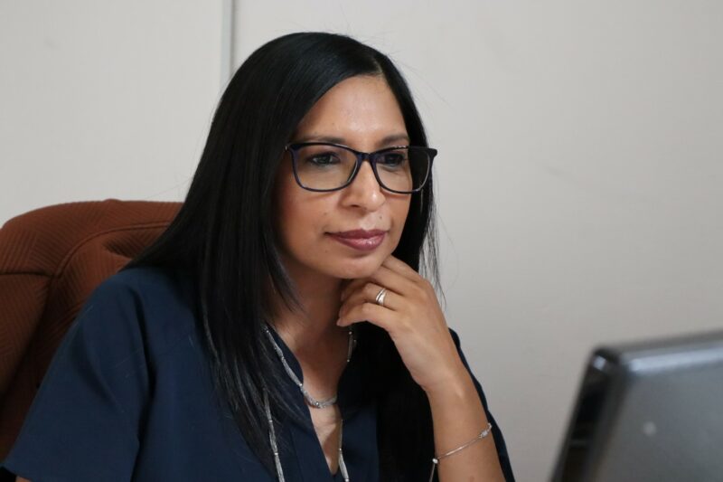 Cherryl is looking at her computer behind her desk with her hand under her cheek