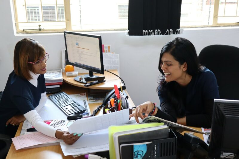 Jessica and Tina are looking at a piece of paper and talking to each other