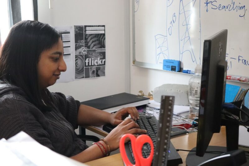 Estella is typing an article on her computer in her office