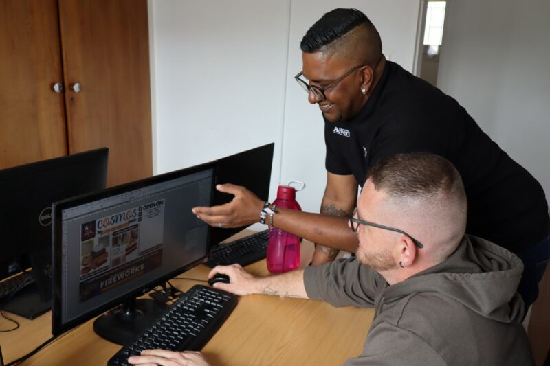 Stevan and Jermain are behind there computers working on an ad design