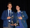 Photo of male and female learner in blue school uniform holding their trophies.