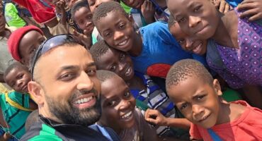 A volunteer poses for a photo with a large crowd of locals during a trip to Malawi.