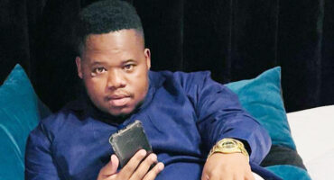 Image of Maskandi artist Dlubheke Khuzwayo holding a phone.