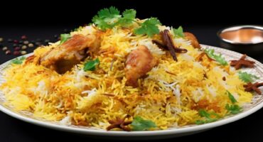 A plate of vibrant chicken biryani garnished with cilantro, star anise, and spices on a dark background, conveying warmth and aromatic flavors.