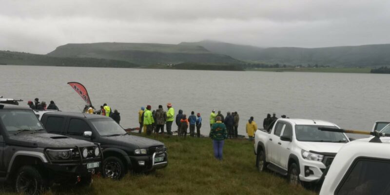 A group of fishermen dressed in the fisherman attire standing outside by a large Chelmsford Dam.