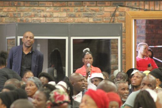 Image of a lady speaking on a micro-phone addressing service delivery issues within her community at the 'Taking Legislature to the People' programme.