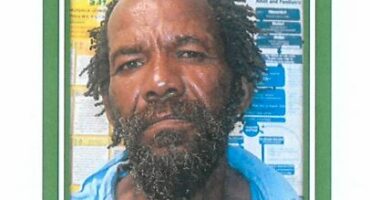 A photo of an elderly man with a dark green border around it and medical pamphlets in the background.