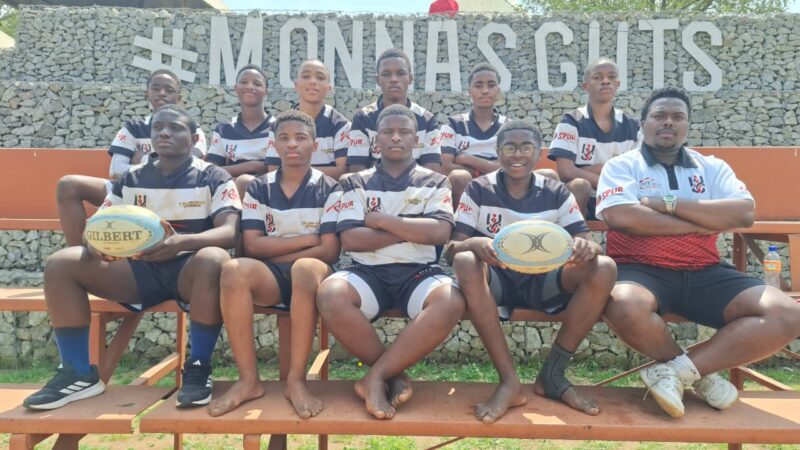 A team of young rugby players are pictured sitting next to each other for a formal team photo.