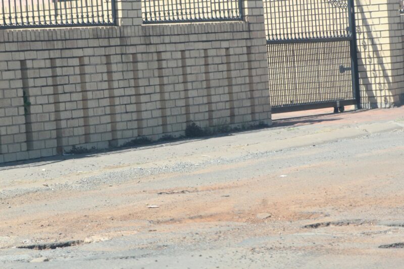 A Suburban road is pictured riddled with potholes.