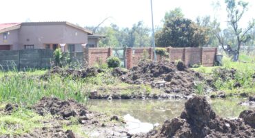 A 'pond' of sewage water is pictured in an open field in front of homes.