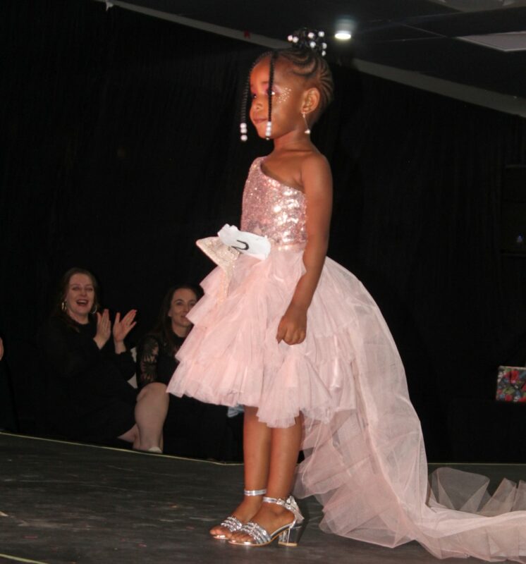 A young pageant queen dressed in beautiful evening wear on the Miss Wonder Woman Beauty pageant Stage in Newcastle.