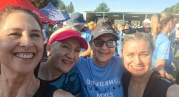 Image of four women, two with caps on, smiling after completing a trail run.