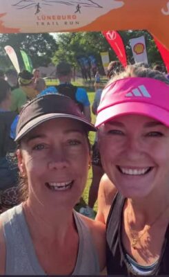 Image of two women with caps on smiling after completing a trail run.