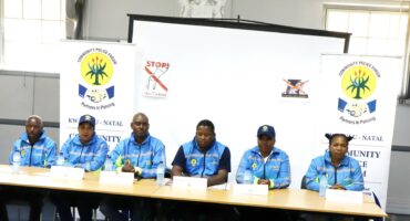 Image of Umzinyathi CPF members in unform bheind a desk at a media briefing discussing GBV and how to stop the trend.