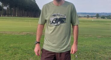 Image of a white man dressed in green shirt and brown shorts standing on the parkrun route.