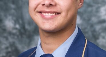 Image of learner from Hoërskool Pionier dressed in blue school uniform with grey background.