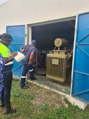 Image of an African man from NERSA with a pen and book in his hand while looking at the transformer.