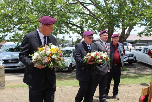 Veteran soldiers holding flowers dressed in uniform and maroon berets.