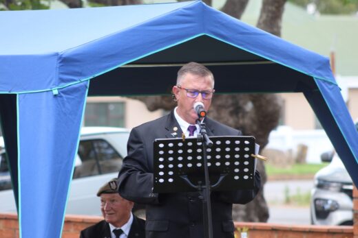 André van Ellinckhuyzen standing behind a podium delivering a speech in open air.