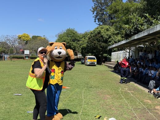 Woman with safety vest standing next to a mascot dressed in a cat suit with big head and safety clothes on.