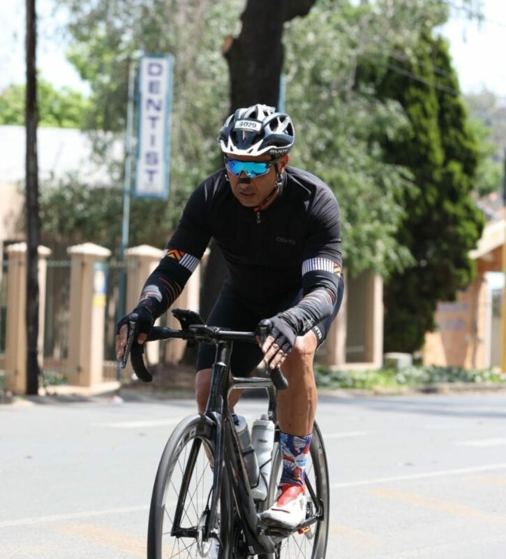 A man is pictured on his bicycle on an open road during a cycling event in Johannesburg. He wears a cycling helmet and cycling gear.