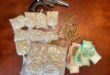 A revolver, several bags of mandrax drugs, scattered bullet casings, and stacks of assorted money notes are displayed on a wooden table after being seized by the Madadeni Police during a stop-a-search-operation.