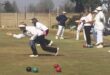 An Image of two people bowling and other people standing at the back wearing bowling clothing at the Vryheid Bowling Club.